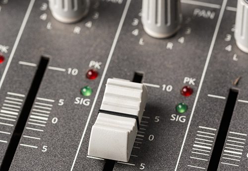 Audio mixing console with sliders and knobs on the channels